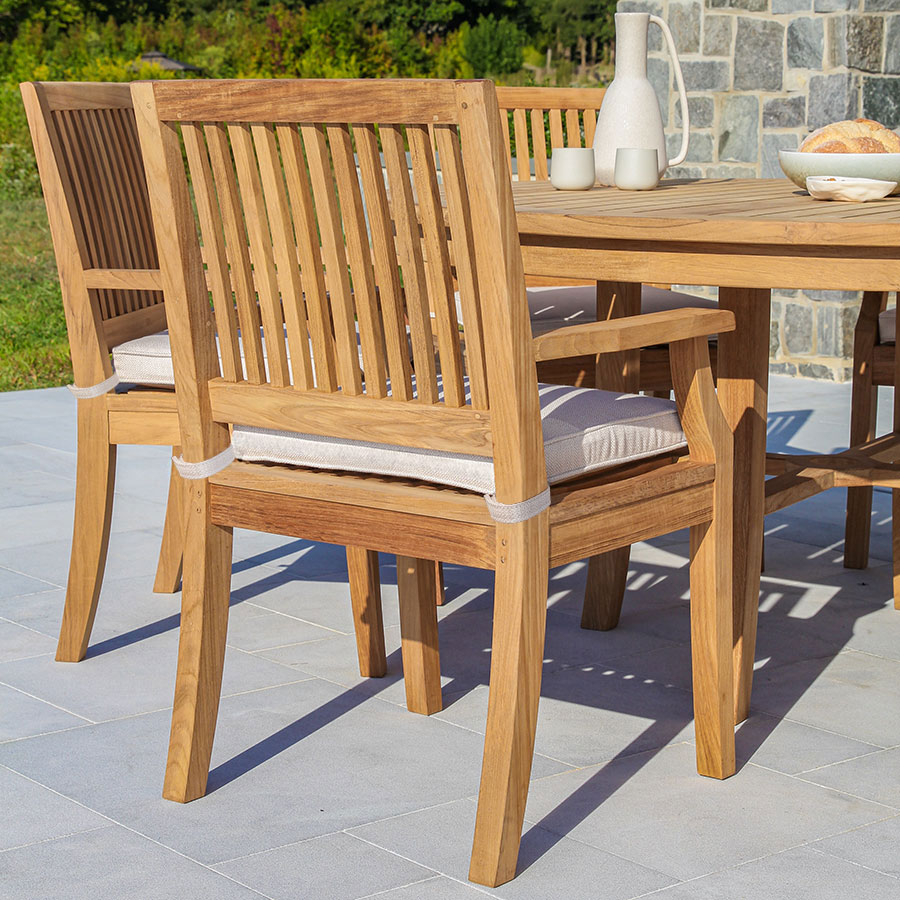 Seneca solid teak wood outdoor dining armchair with slatted backrest.